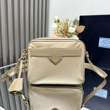 Beige boxy camera bag with a front zip pocket on a display stand