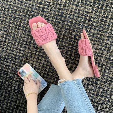 Pink quilted slide sandals worn by a person in jeans