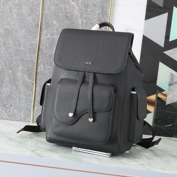 Black grained backpack with a clasped flap and side pockets, photographed against a marble wall