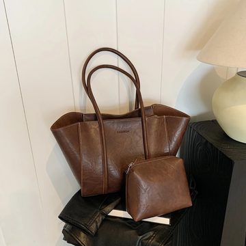 Brown leather-look tote with long handles and a matching small pouch on a stool