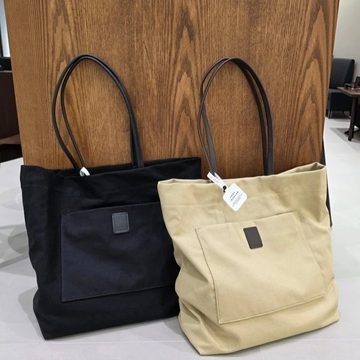 Black and natural canvas tote bags with long handles and a front patch pocket