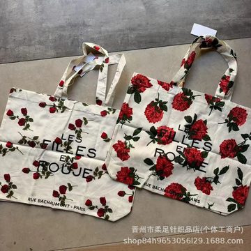 Two cream canvas tote bags printed with red roses, laid flat