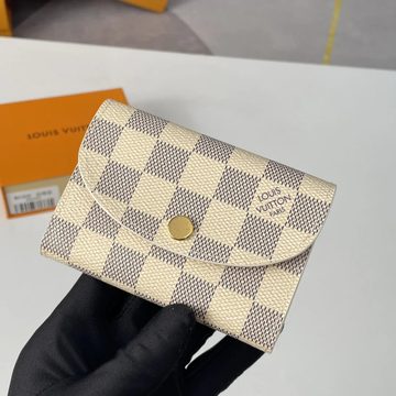 Cream and grey check-pattern wallet with a curved flap and gold snap, held in a gloved hand
