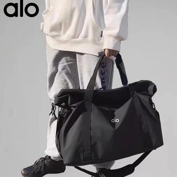 Black nylon gym holdall carried by a person in grey trousers